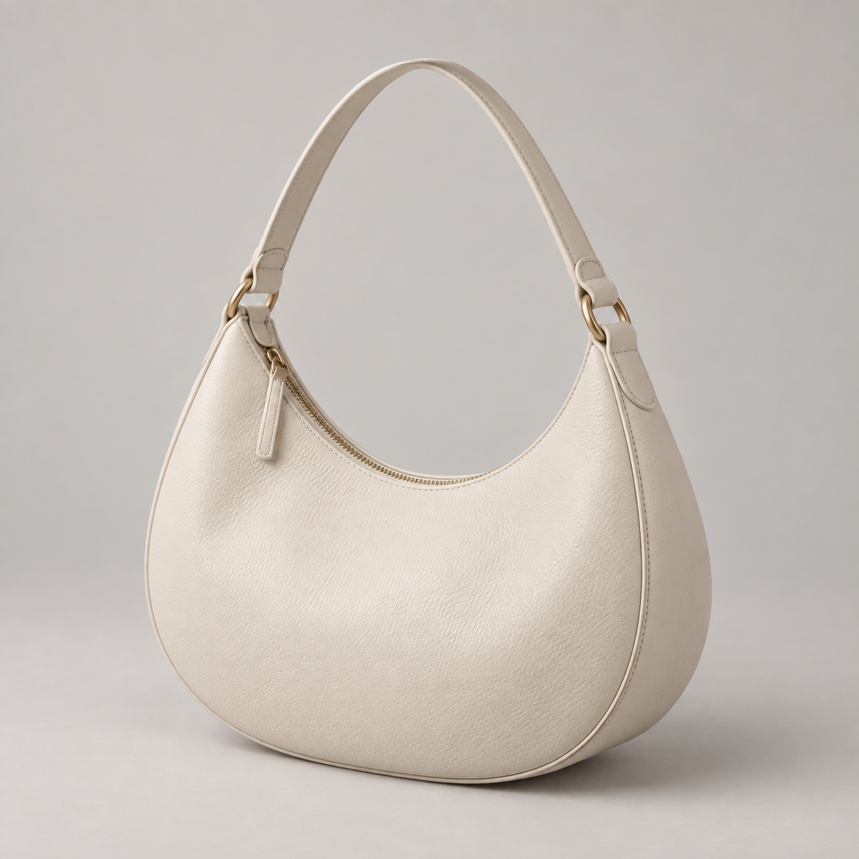 Ivory Crescent: Soft crescent-shaped shoulder bag with a curved strap and a minimal zip top. Illustrative design reference.